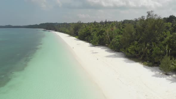 Aerial: Woman on white sand beach turquoise water tropical coastline caribbean sea