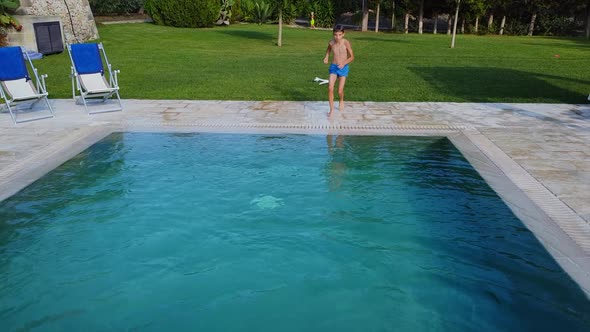 Boy Child Jumping Into a Pool with Blue Water Leisure Activities on a Hot Day