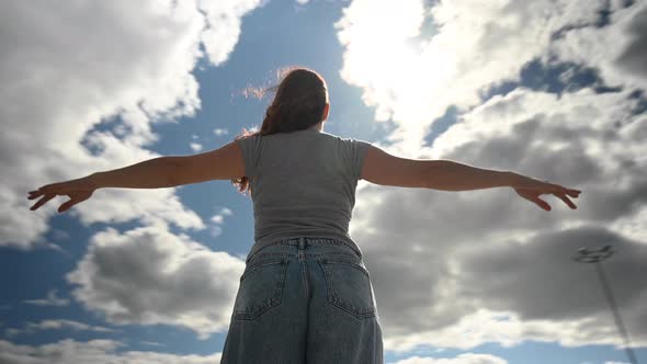 Caucasian Woman Spread Her Arms Like Wings Against a Cloudy Sky