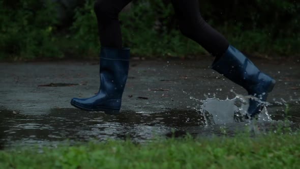Closeup  Girl in Blue Rubber Boots Running Through the Puddles