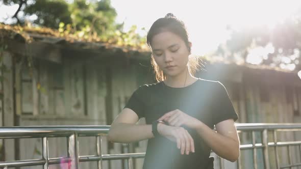 Attractive young Asian woman athlete checking at heart rate on a smartwatch.