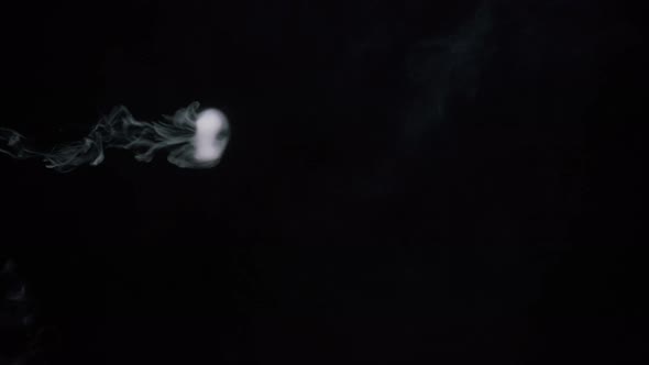 Closeup of Smoke Rings Smoking Hookah or Cigarette in Dark Studio View Side of Blowing Out Puffs of