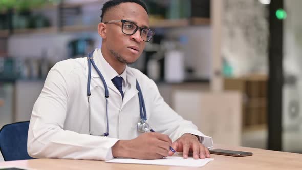 Focused African Male Doctor Doing Paperwork in Office