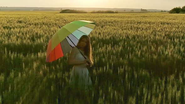 Girl with Multicolored Umbrella Walking in Field