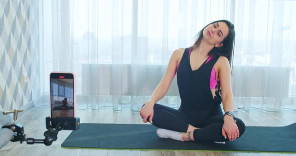 Woman is Recording on Her Phone the Yoga Class Stretching on a Yoga Mat