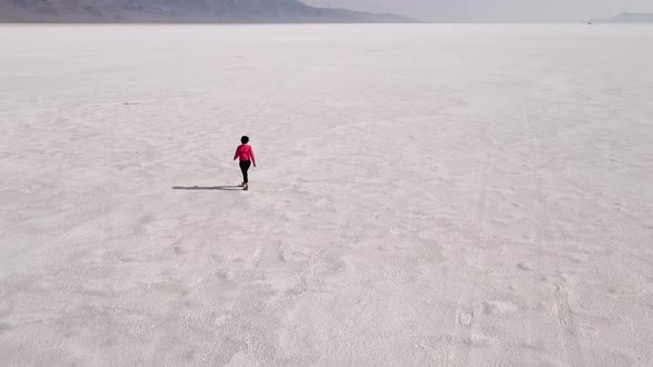 Aerial shot of an Asian woman hiking across the Bonneville Salt Flats flats