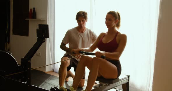 Sporty woman exercising on fitness machine with personal coach
