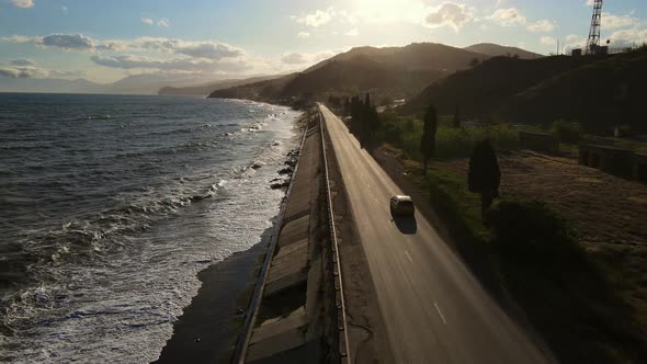 A Car Drives Along a Coastal Road Over a Picturesque Rocky Shore