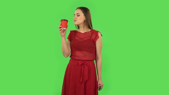 Tender Girl in Red Dress Is Enjoying Coffee. Green Screen