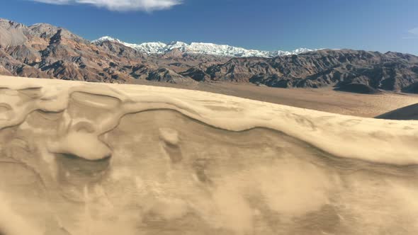 Sand Dunes Aerial with High Snow Summit and Peaks on Motion Background  Nature