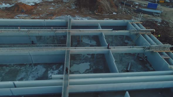 Worker Walks Along Footbridge Over Basin for Waste Water