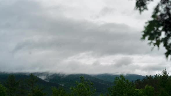 Fog and clouds raining over lush green forest and mountains timelapse (4k)