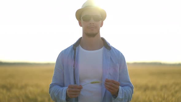 Man Farmer in a Hat Walking in Wheat Field