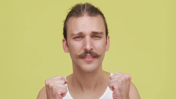 Interesting Young Man with Mustaches Expressing Excitement Over Yellow Background Closeup