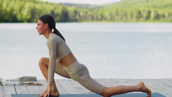 Young Fit Woman Practicing Yoga on Pier by Lake