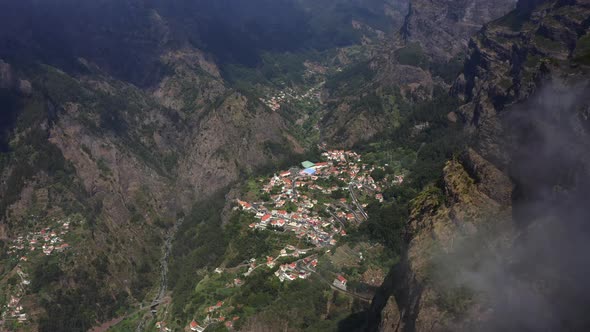 AERIAL: Small town between clouds in the mountains in Madeira