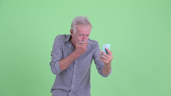 Stressed Senior Bearded Man Using Phone and Looking Shocked