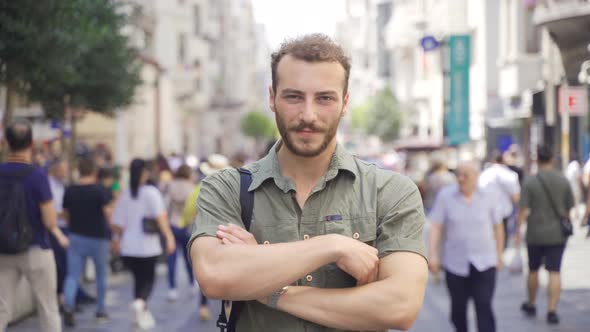 Young man standing in the middle of the crowd looking at the camera.