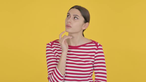 Pensive Spanish Woman Thinking on Yellow Background