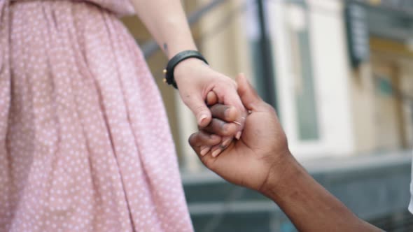 Young Man Kisses the Hand of His Girlfriend While Walking in the City Closeup