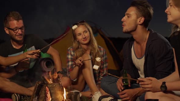 Handsome Caucasian Male with Light Bristle Eating Fried Marshmallow with Botlled Beer in Hand