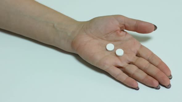 Female hand holds pills for headache. Migraine medicine, antibiotics