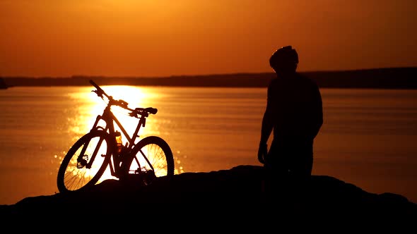 Rider resting on cycling trip in nature. Mountain biker looking at view on bike trail