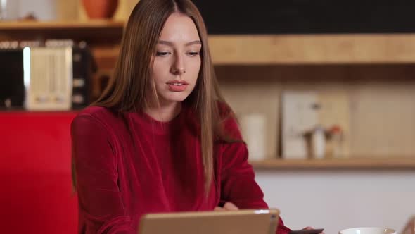 Young Woman Making Purchase Online, Typing Credit Card Details on tabletPC in the Modern Kitchen