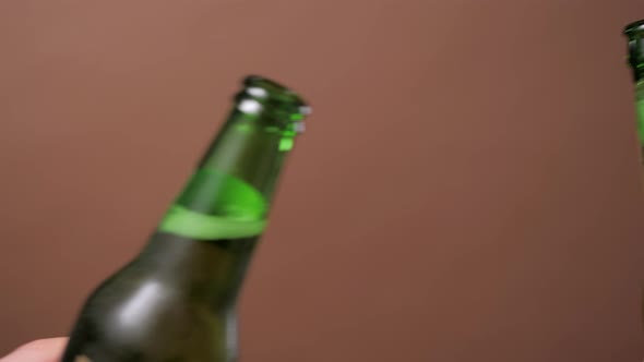 Closeup of Hands Toasting with Bottles of Beer