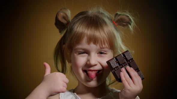Closeup Portrait of Teen Child Kid with Milk Chocolate Bar Showing Thumb Up on Dark Background