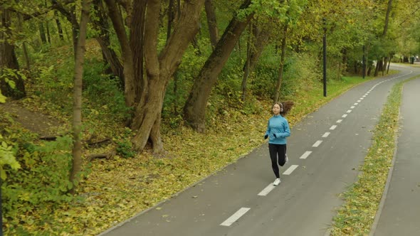 Slow Motion Young Female Jogging in Park in Golden Autumn