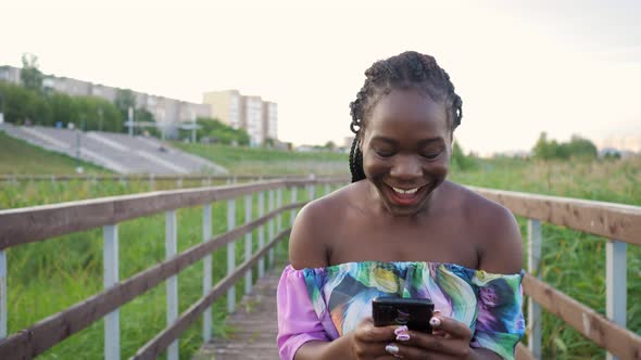 African Woman with Phone Jumping with Happiness on Wooden Bridge