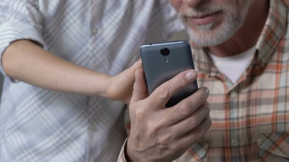 Grandson Teaching Granddad to Use Smartphone Application, Showing Thumbs Up