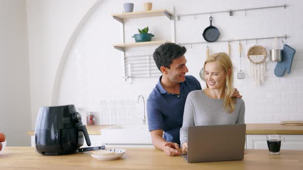 Couple Using Laptop in Kitchen