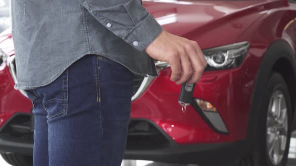 Cropped Shot of a Man Holding Car Keys Standing in Front of an Auto