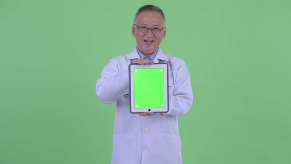 Happy Mature Japanese Man Doctor Talking While Showing Digital Tablet