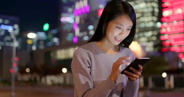 Young Woman use of mobile phone in city at night