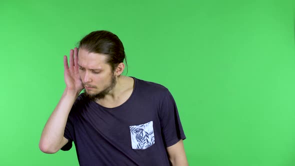 Portrait of a Young Man Holding His Hand Near His Ear Trying to Listen to Interesting News