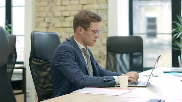 Side View of Exhausted Stressed Caucasian Man in Eyeglasses Working on Laptop. Portrait of Confident