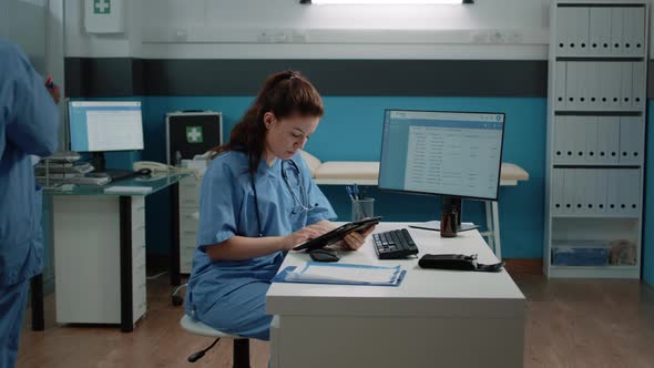Medical Assistant Typing on Tablet Screen and Checking Computer