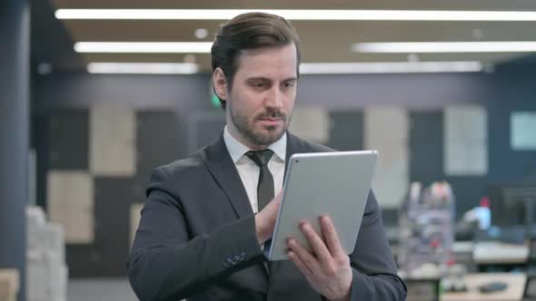 Portrait of Businessman Browsing Internet on Tablet in Office