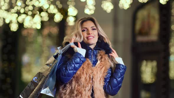 Portrait of Glamour Smiling Woman Wearing Fur Clothes Holding Shopping Bags Gifts Looking at Camera