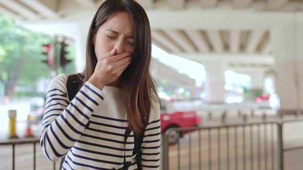 Woman sneezing at outdoor in Hong Kong city 