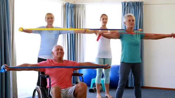 Trainer assisting senior citizens in performing stretching exercise