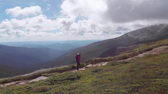 Aerial View of a Traveler with a Backpack Climbing By Mountain Range. Epic Shot