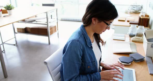 Female executive sitting at desk and using digital tablet