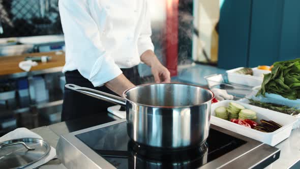 Close-up: The chef adds ingredients to the pot. The process of preparing food in a restaurant.