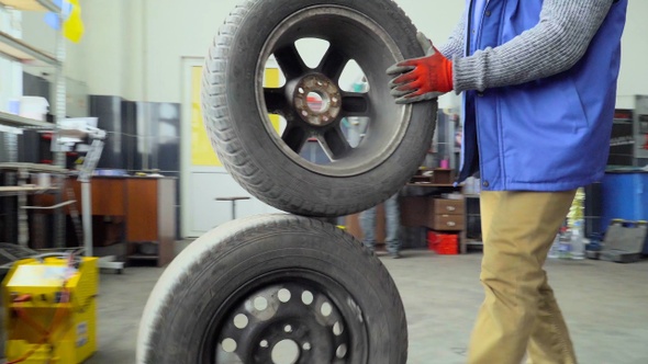 Worker rolls a two wheels in a car repair shop