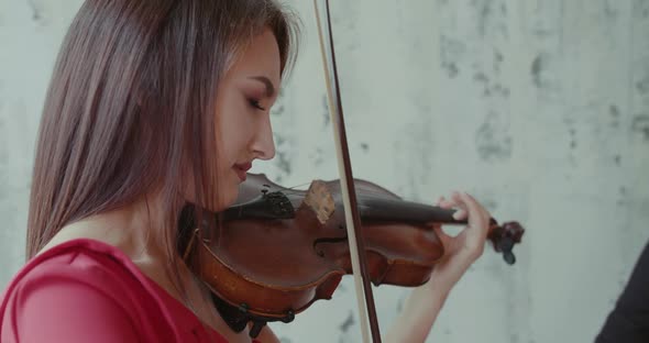 Portrait of Admiring Girl Playing the Violin Emotionally at Background Indoor