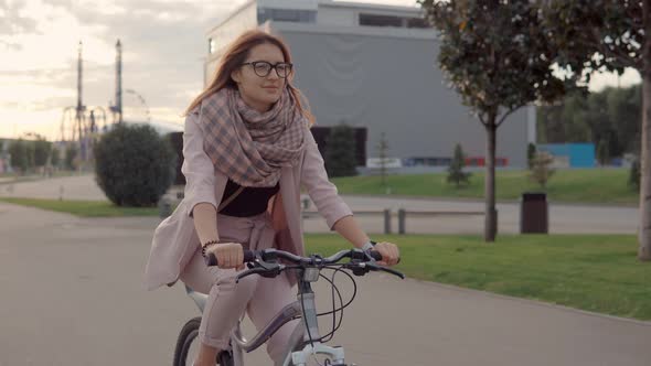 Happy Teenager Girl Is Driving a Bike in a Park in Twilight